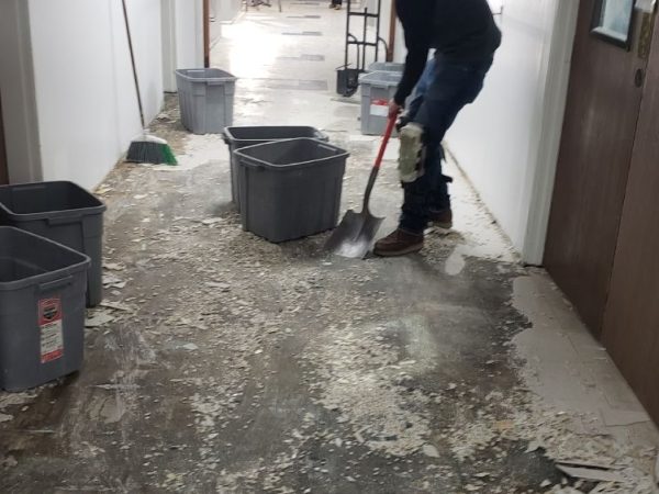 professional shoveling scrapings from floor during demolition process